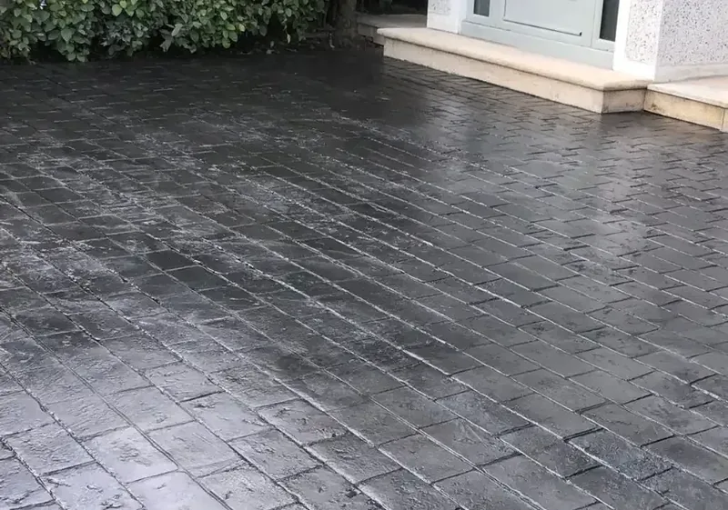 Dark grey imprinted concrete driveway in Dublin after rain