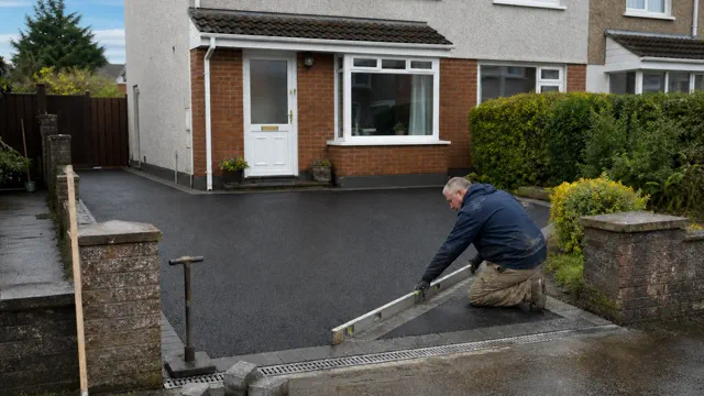 Contractor checking levels on a newly laid tarmac driveway outside an Irish semi-detached house
