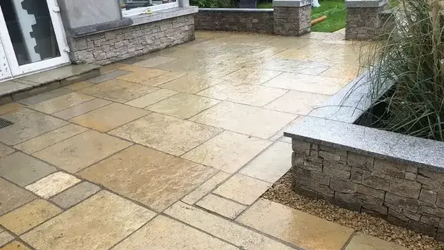 Sandstone patio with stone-clad raised beds and granite copings at a Dublin house