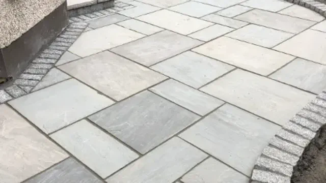 Indian sandstone patio slabs laid with a granite cobble border beside an Irish house